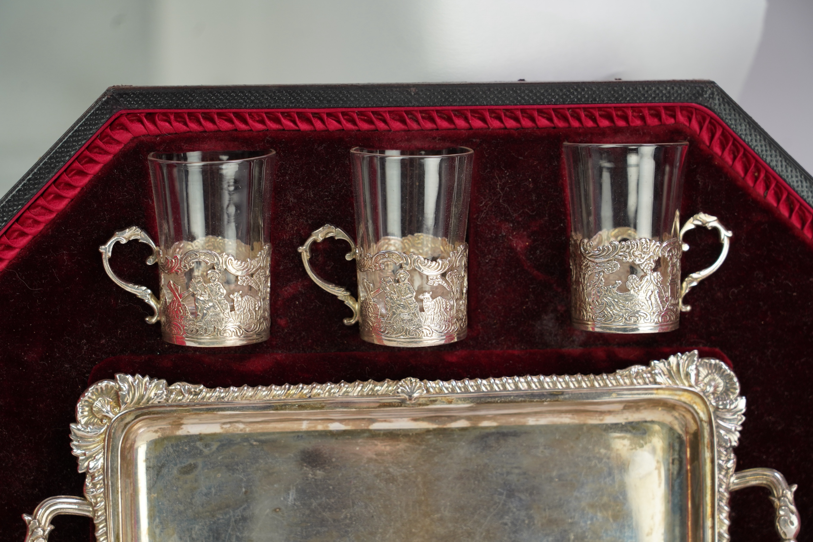 An Edwardian cased silver small two handled serving tray with six matching silver mounted glass liqueur tots, by Atkin Brothers